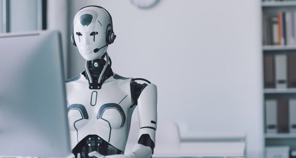 Android AI robot sitting at the desk and working in the office: artificial intelligence, business and automation concept