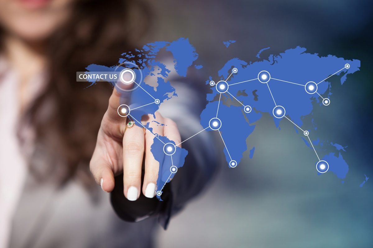 Businesswoman pressing contact us button on world map on digital touch screen. Customer service support concept.