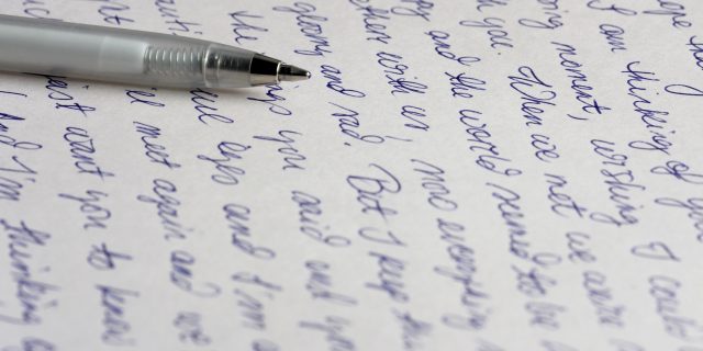 A handwritten letter with a silver ballpoint pen.